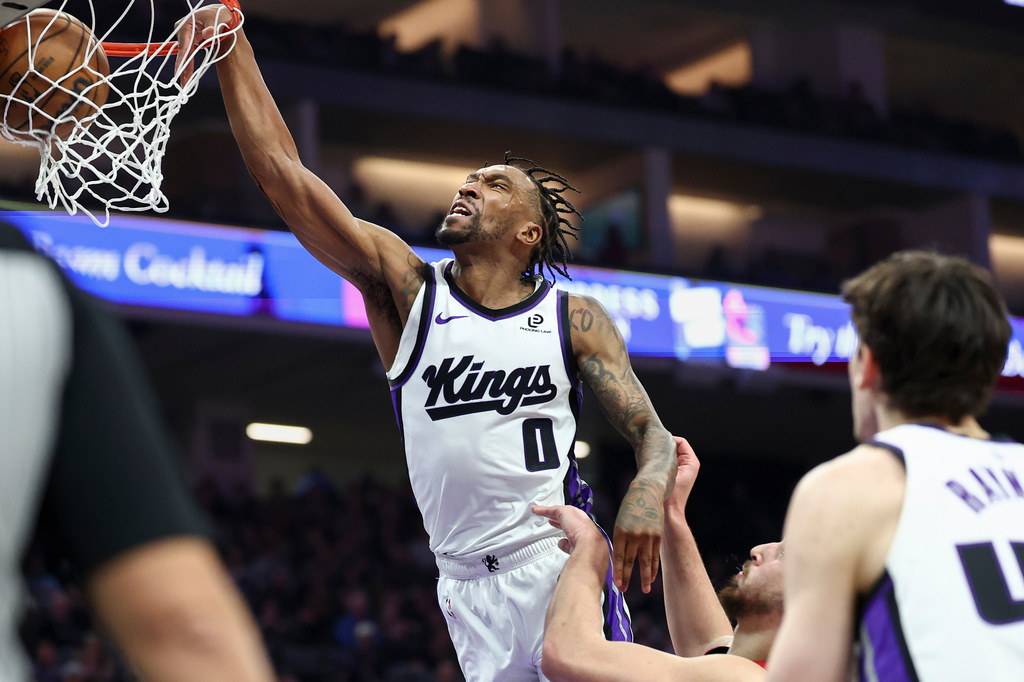 Sacramento Kings guard Malik Monk (0) dunks with Houston Rockets center Alperen Sengun, center, defending during the first half of an NBA basketball game, Sunday, Jan. 11, 2026, in Sacramento, Calif. (AP Photo/Sara Nevis)