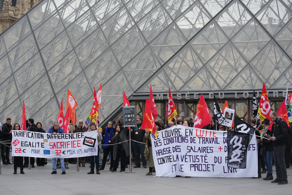 Unionists display a banner and union flags outside the Louvre museum after employees have voted to extend a strike that has disrupted operations at the world's most visited museum, Wednesday, Dec. 17, 2025 in Paris. (AP Photo/Christophe Ena)