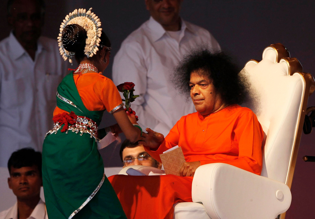 FILE - Indian spiritual leader Sathya Sai Baba, right, receives a flower from a girl at a function to meet his devotees in New Delhi, India, April 10, 2010. (AP Photo/Mustafa Quraishi, File)