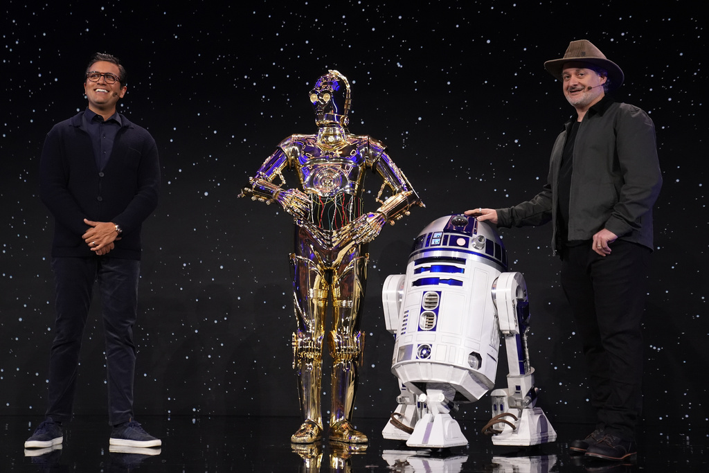 Asad Ayaz, left, and Dave Filioni stand on stage with C-3PO and R2-D2 during an LEGO news conference ahead of the CES tech show Monday, Jan. 5, 2026, in Las Vegas. (AP Photo/Abbie Parr)