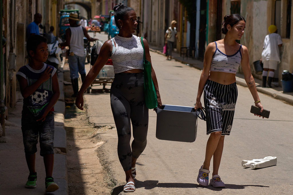 People carry a portable power charger during a blackout in Havana, Cuba, Tuesday, July 14, 2026. (AP Photo/Ramon Espinosa)