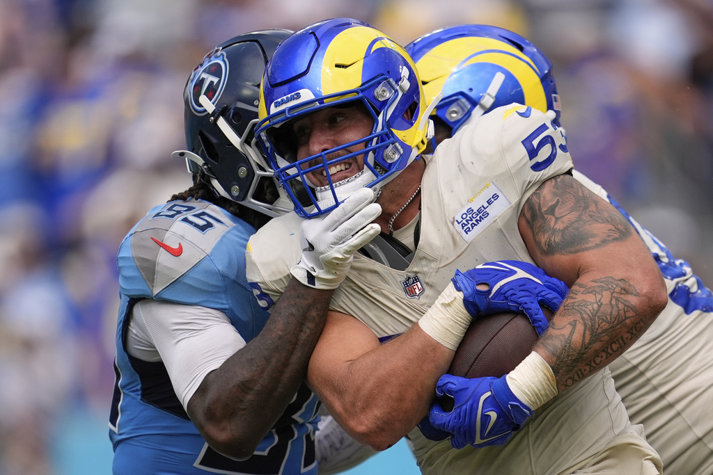 Los Angeles Rams linebacker Nate Landman, right, runs with the ball after picking up a fumble by Tennessee Titans quarterback Cam Ward as tight end Chig Okonkwo tries to tackle him during the second half of an NFL football game Sunday, Sept. 14, 2025, in Nashville, Tenn. (AP Photo/George Walker IV)