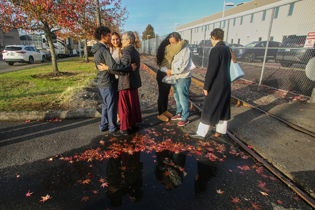 Immigrants from Portland, including Victor Cruz, center right, in the gray hooded sweatshirt, embrace family members after being released on bond in Tacoma, Wash., Friday, Nov. 7, 2025. (AP Photo/Cedar Attanasio)