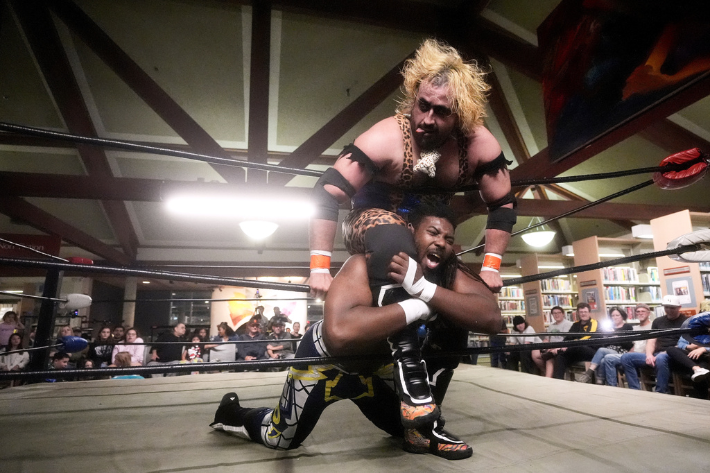 Wrestler Jaguar Montoya, top, applies a hold against OC Hayes during a Lucha Libro pro wrestling event at Benicia Public Library Saturday, May 2, 2026, in Benicia, Calif. (AP Photo/Jeff Chiu)
