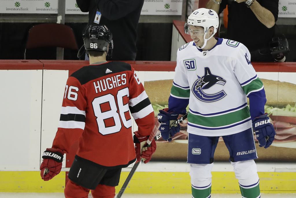 FILE - Vancouver Canucks' Quinn Hughes, right, talks to his brother New Jersey Devils' Jack Hughes, left, before of an NHL hockey game Saturday, Oct. 19, 2019, in Newark, N.J. The Devils won 1-0. (AP Photo/Frank Franklin II, file)
