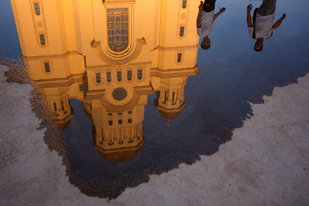The National Cathedral is reflected in a puddle as youth gather for the Procession of Lights, part of a four-day program of the International Meeting of Orthodox Youth (ITO), in Bucharest, Romania, Wednesday, Sept. 2, 2026. (AP Photo/Andreea Alexandru)