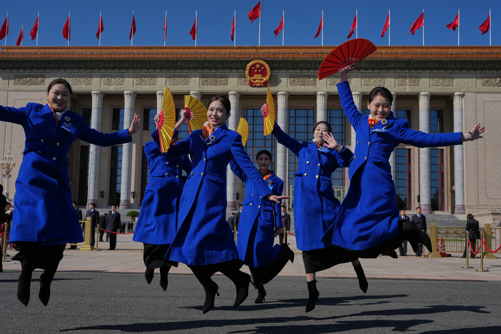 Bus ushers jump for photos in front of the Great Hall of the People where a plenary session of the National People's Congress (NPC) is held in Beijing, Monday, March 9, 2026. (AP Photo/Ng Han Guan)