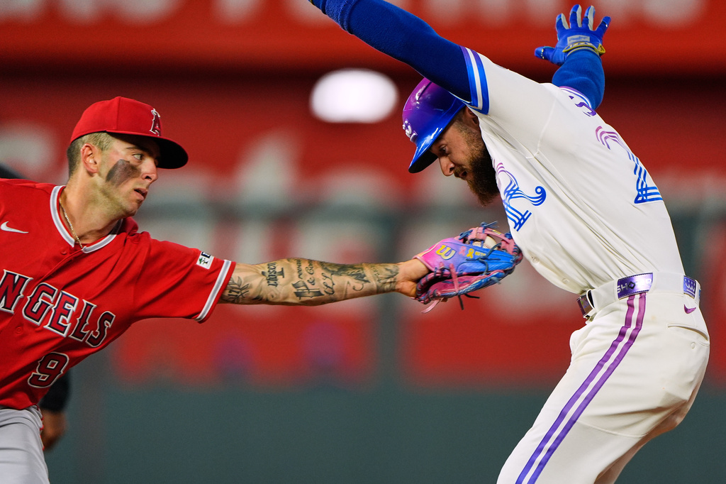 Kansas City Royals' Kyle Isbel is tagged out by Los Angeles Angels shortstop Zach Neto (9) after getting caught off base during the seventh inning of a baseball game Saturday, April 25, 2026, in Kansas City, Mo. (AP Photo/Charlie Riedel)