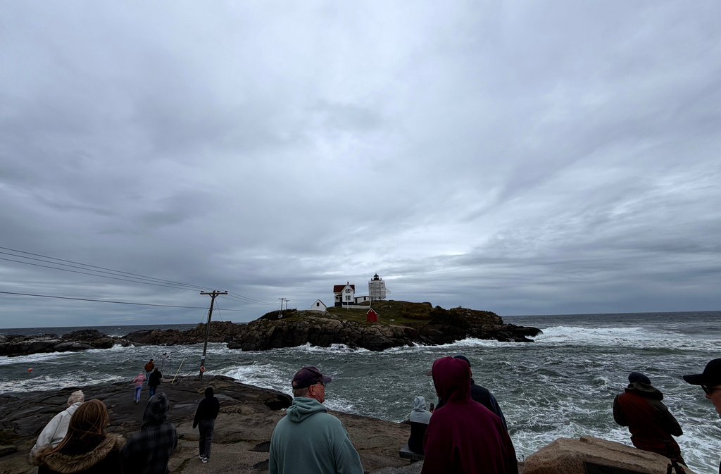 In this photo made with a smartphone, people watch the waves at Nubble Lighthouse in York, Maine, during a nor'easter, Saturday, Sept. 26, 2026. (AP Photo/Caleb Jones)