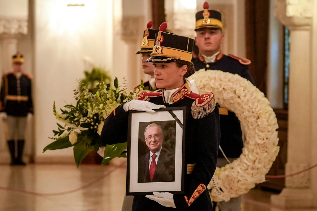 Honor guard soldiers carry a picture of the late Ion Iliescu, Romania's first freely elected president after the fall of communism in 1989, ahead of his coffin at the Cotroceni Presidential Palace, in Bucharest, Romania, Wednesday, Aug. 6, 2025.(AP Photo/Vadim Ghirda)