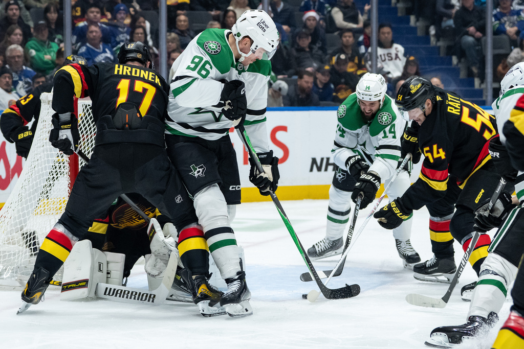 Vancouver Canucks goaltender Kevin Lankinen (32) stops Dallas Stars' Mikko Rantanen (96) and Jamie Benn (14) as Vancouver's Filip Hronek (17), and Aatu Raty (54) defend during the second period of an NHL hockey game in Vancouver, on Thursday, Nov. 20, 2025. (Ethan Cairns/The Canadian Press via AP)