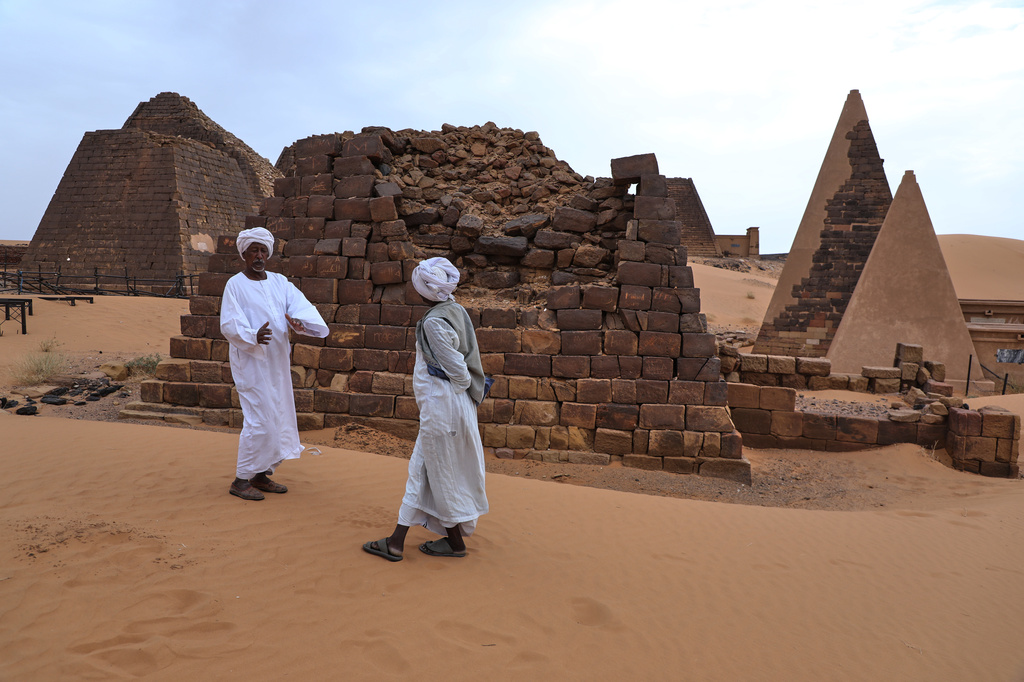 A guide, left, speaks with a visitor at the Meroe archaeological site in Bejrawiya, Sudan, Sunday, Aug. 2, 2026. (AP Photo/Mohnd Blal)