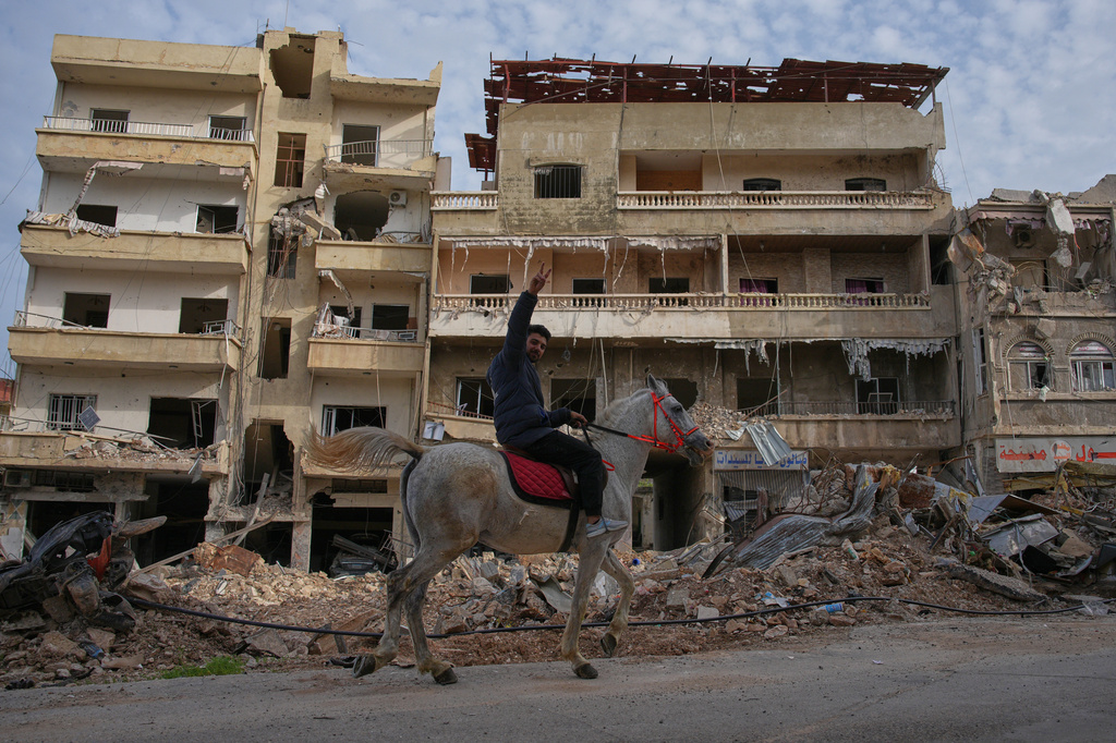 A man rides a horse past the site of buildings destroyed in an Israeli airstrike, in Jibchit, southern Lebanon, Friday, April 17, 2026, following a ceasefire between Israel and Hezbollah. (AP Photo/Hassan Ammar)