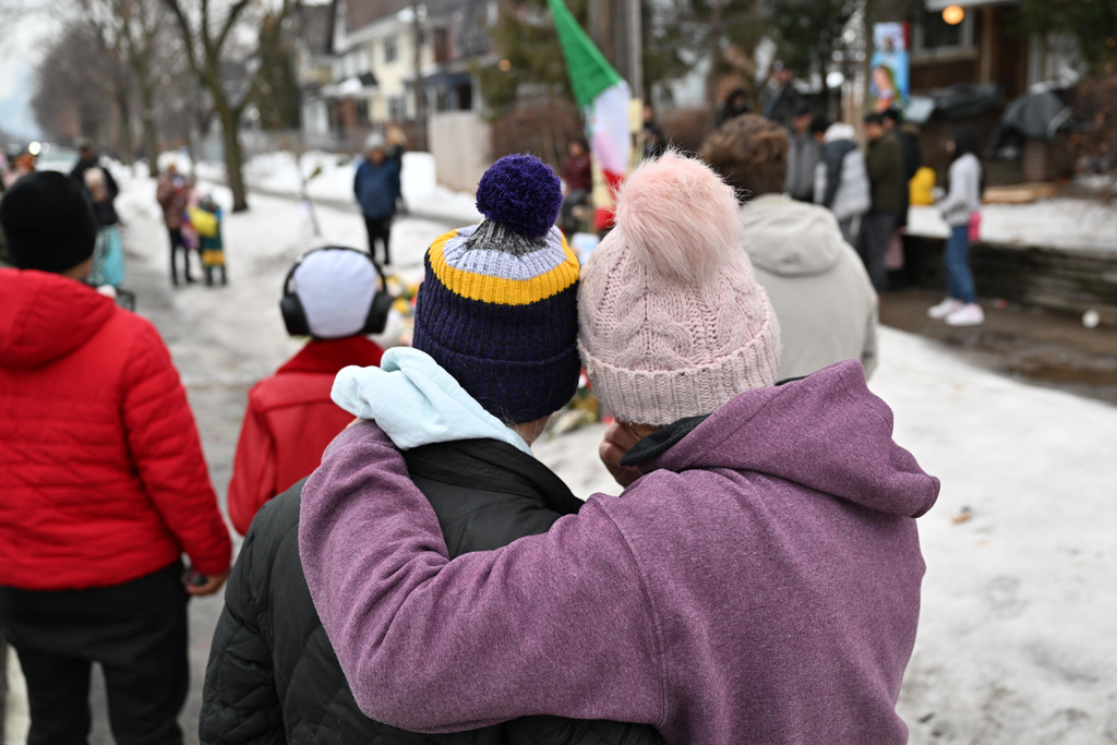 People gather around a makeshift memorial honoring the victim of a fatal shooting involving federal law enforcement agents, inear the site of the shooting, Thursday, Jan. 8, 2026, in Minneapolis. (AP Photo/Tom Baker)