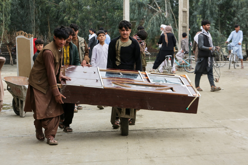 Residents carry furniture in a wheelbarrow as they clear an area damaged by heavy flooding in Jalalabad, Afghanistan, Saturday, April 4, 2026. (AP Photo/Wahidullah Kakar)