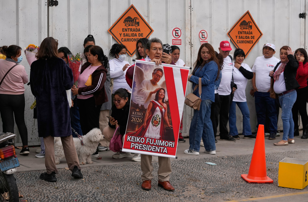 A supporter of President-elect Keiko Fujimori, holds a poster depicting her with her father, former President Alberto Fujimori, outside of her home in Lima, Peru, Friday, July 3, 2026. (AP Photo/Martin Mejia)