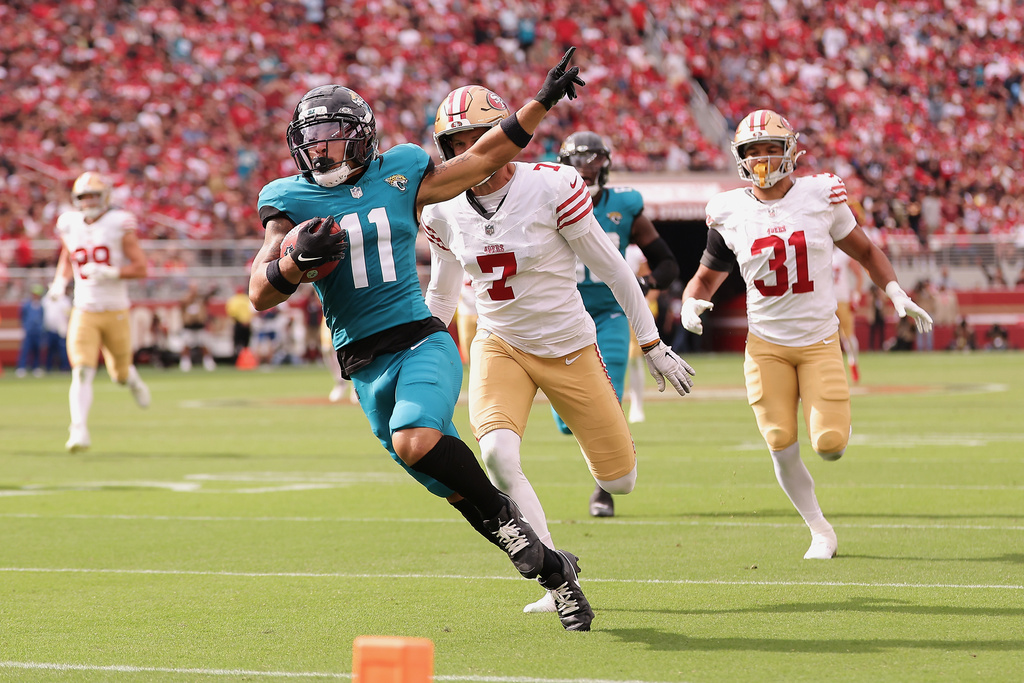 Jacksonville Jaguars' Parker Washington (11) gestures while returning a punt for a touchdown in front of San Francisco 49ers punter Thomas Morstead (7) and Isaac Guerendo (31) during the second half of an NFL football game in Santa Clara, Calif., Sunday, Sept. 28, 2025. (AP Photo/Kelley L. Cox)