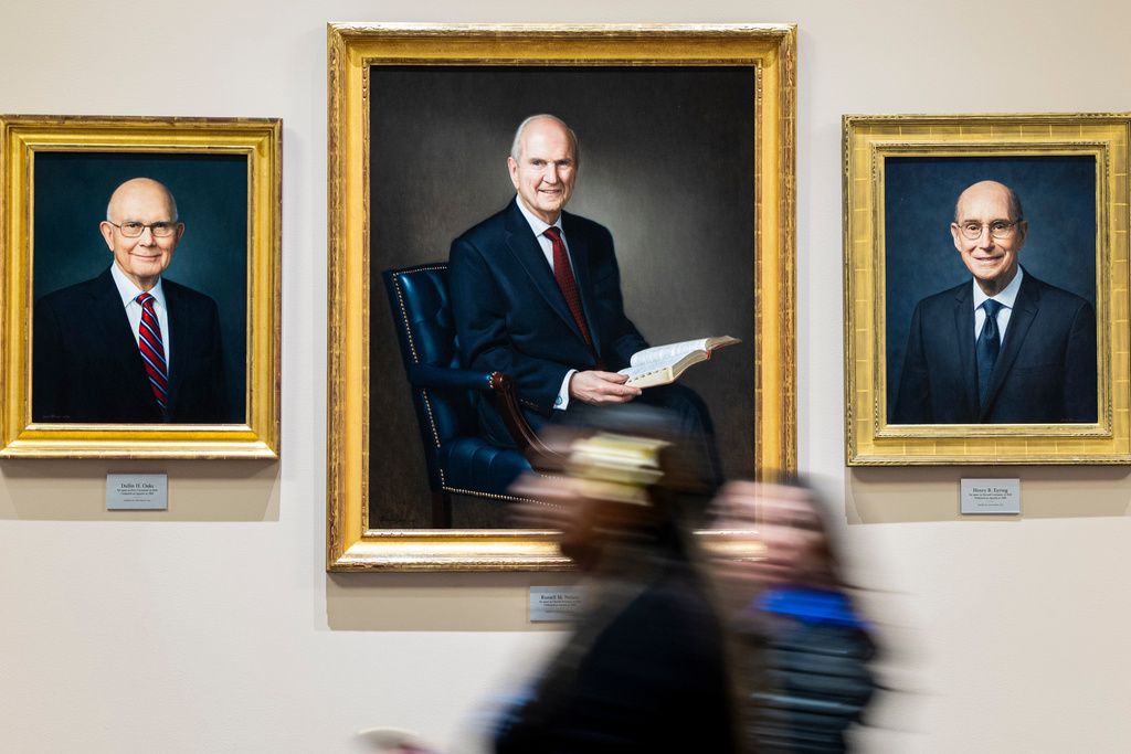 People pass by portraits of the previous church's First Presidency, from left, Dallin H. Oaks, first counselor in the First Presidency, Russell M. Nelson, 17th president and prophet of The Church of Jesus Christ of Latter-day Saints, and President Henry B. Eyring, second counselor in the First Presidency, before the Saturday morning session of the 195th Semiannual General Conference of The Church of Jesus Christ of Latter-day Saints in the Conference Center in Salt Lake City on Saturday, Oct. 4, 2025. (Isaac Hale/The Deseret News via AP)