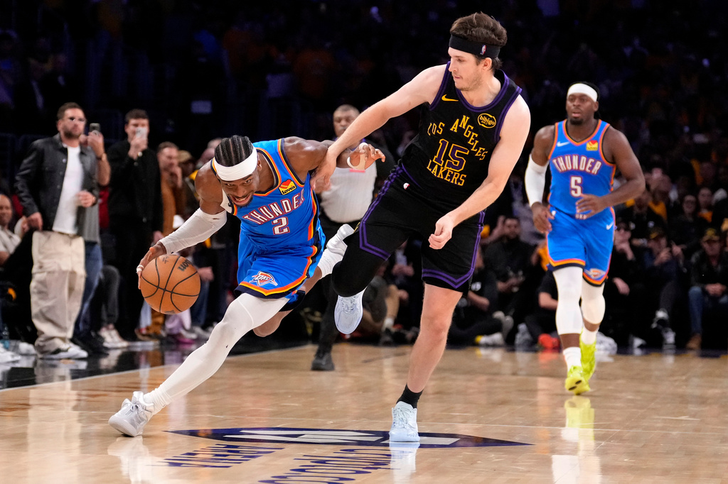 Oklahoma City Thunder guard Shai Gilgeous-Alexander, left, drives by Los Angeles Lakers guard Austin Reaves during the second half of Game 4 in a second-round NBA basketball playoffs series Monday, May 11, 2026, in Los Angeles. (AP Photo/Mark J. Terrill)