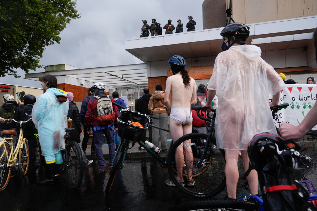 Federal agents stand and look over protesters during the Naked Bike Ride protest at the U.S. Immigration and Customs Enforcement facility on Sunday, Oct. 12, 2025, in Portland, Ore. (AP Photo/Jenny Kane)