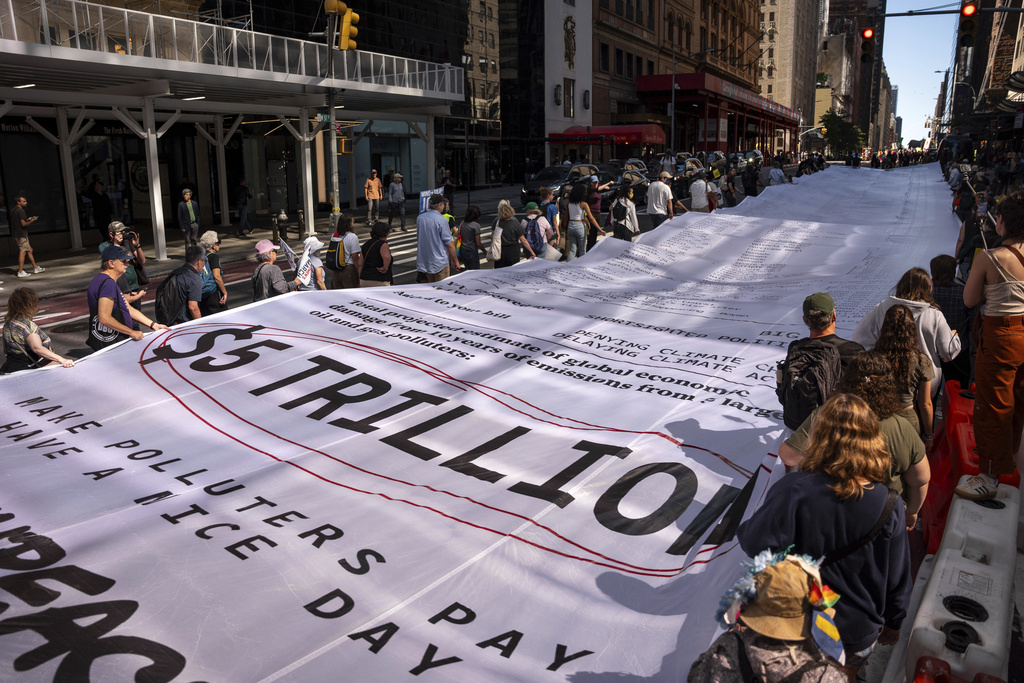 People carry a "Climate Polluters Bill" the length of an Olympic swimming pool (50 meters long) through Manhattan at the "Make Billionaires Pay" climate protest, Saturday, Sept. 20, 2025, in New York. The bill was created by Greenpeace and lists the costs of hundreds of climate-related natural disasters (AP Photo/Angelina Katsanis)