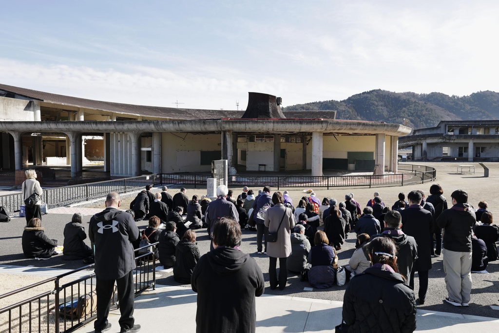 Peopel mourn in front of former Okawa Elementary School where lots of children and teachers from the school lost their lives by the massive tsunami in Ishinomaki, Miyagi Prefecture, northern Japan Wednesday, March 11, 2026, as the country marked the 15th anniversary of the massive earquake, tsunami and nuclear disaster. (Mizuki Sakai/Kyodo News via AP)
