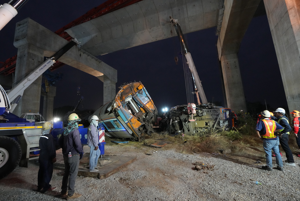 Rescuers try to lift the wreckage after a construction crane fell onto a passenger train in Nakhon Ratchasima province, Thailand, Wednesday, Jan. 14, 2026. (AP Photo/Sakchai Lalit)