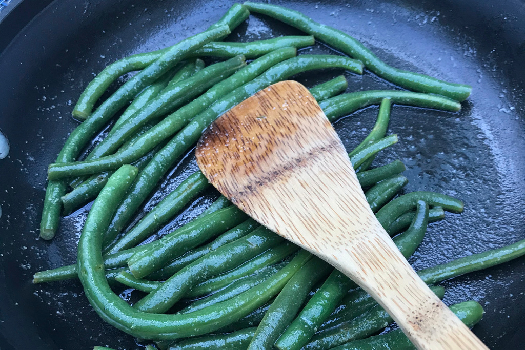 FILE - A plate of green beans picked from a home garden is prepared in a saute pan in Chatham, Mass., on July 28, 2021. (AP Photo/Carolyn Lessard, File)