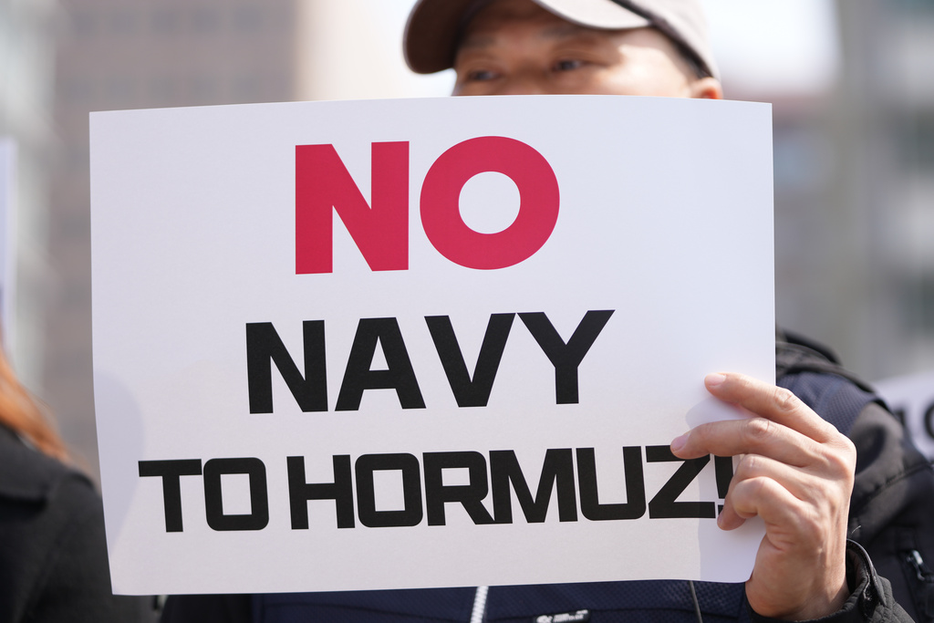 A protester holds a sign against Donald Trump's demands to multiple countries to send warships to keep the Strait of Hormuz open, near the U.S. Embassy in Seoul, South Korea, Monday, March 16, 2026. (AP Photo/Lee Jin-man)