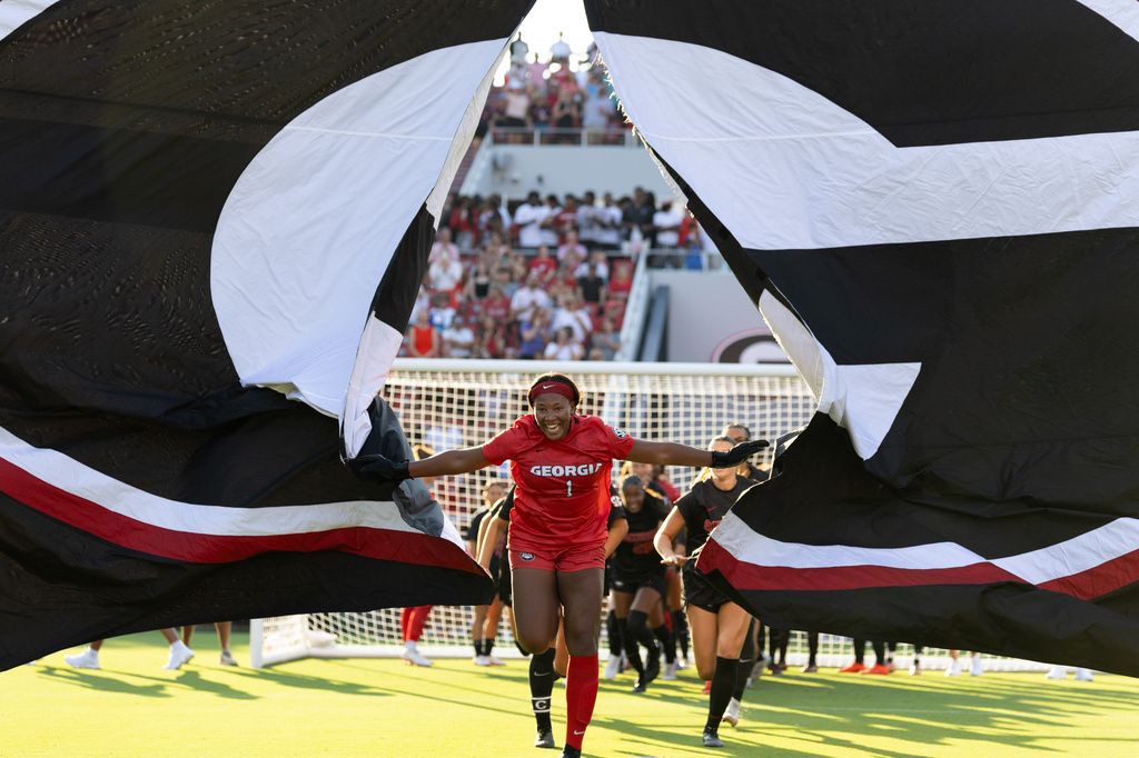 Georgia goalkeeper Jordan Brown (1) leads the team through a banner before the match against James Madison at Sanford Stadium in Athens, Ga, Thursday, Aug. 20, 2026, ahead of a one-off match commemorates the 30th anniversary of the 1996 Olympic women's soccer gold-medal match played at Sanford Stadium. (Evan Frilingos/The Red & Black via AP)