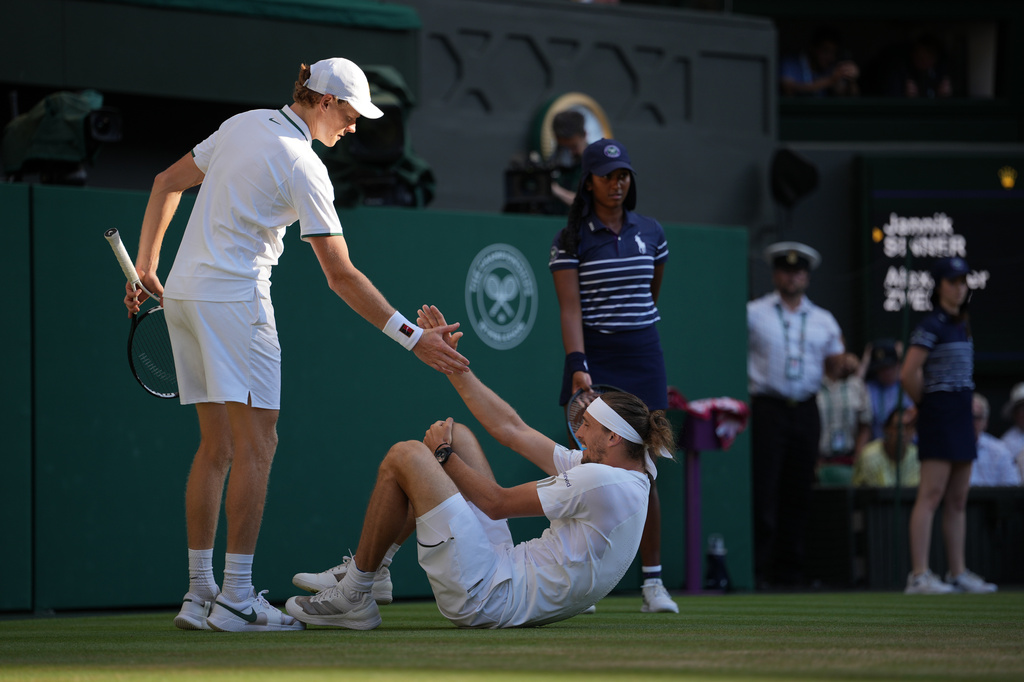 Jannik Sinner of Italy, left helps up Alexander Zverev of Germany who fell during the men's singles final at Wimbledon Tennis Championships in London, Sunday, July 12, 2026. (AP Photo/Kin Cheung)