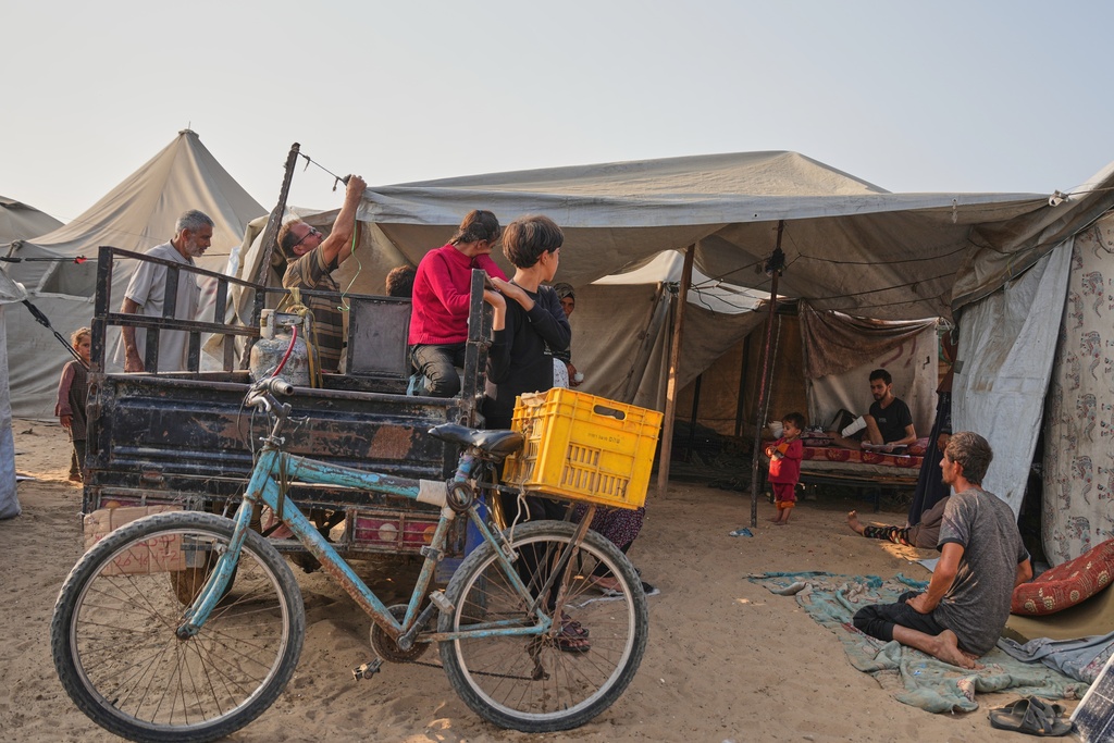 Yassin Marouf, 23, second from right, who lost his left foot and suffered a severe injury to his right leg after Israeli shelling in May, sits on a mattress in a tent surrounded by family and neighbors in Zawaida, central Gaza, Thursday, Nov. 6, 2025. (AP Photo/Abdel Kareem Hana)