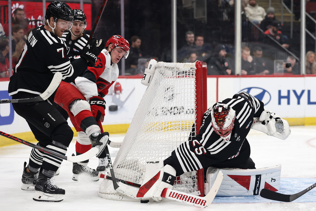 New Jersey Devils goaltender Jacob Markstrom (25) reaches for a puck against Carolina Hurricanes right wing Jackson Blake (53) during the first period of an NHL hockey game Saturday, Jan. 17, 2026, in Newark, N.J. (AP Photo/Adam Hunger)