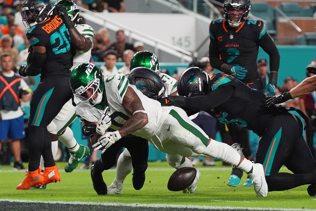 New York Jets running back Braelon Allen (0) fumbles the ball after taking a hit from Miami Dolphins cornerback Jack Jones, rear, in the first half of an NFL football game, Monday, Sept. 29, 2025, in Miami Gardens, Fla. (AP Photo/Marta Lavandier)