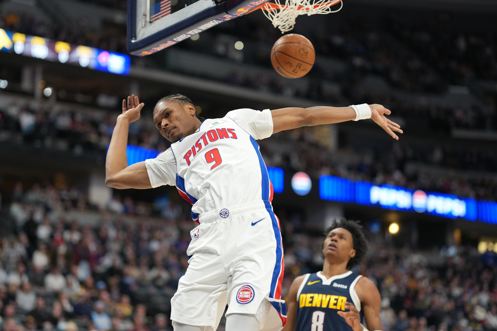 Detroit Pistons guard Ausar Thompson dunks the ball for a basket over Denver Nuggets guard Peyton Watson in the first half of an NBA basketball game Tuesday, Jan. 27, 2026, in Denver. (AP Photo/David Zalubowski)
