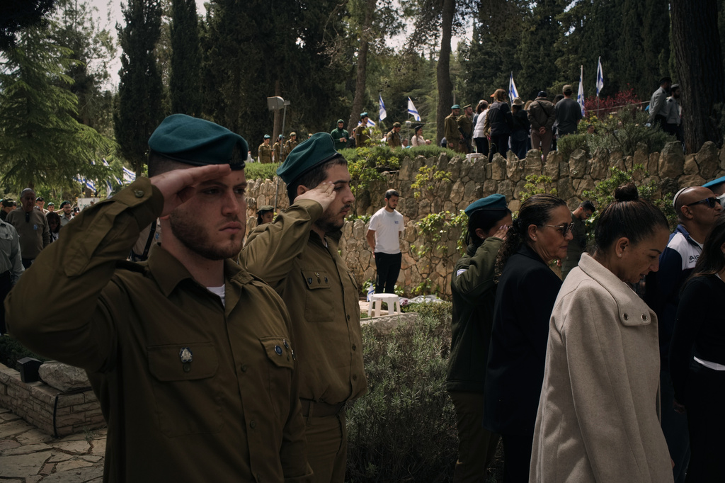 People stand still to observe two minutes of silence as air raid sirens sound, marking Israel's annual Memorial Day for the soldiers who died in the nation's conflicts and victims of nationalistic attacks at Mount Herzl military cemetery in Jerusalem, Tuesday, April 21, 2026. (AP Photo/Leo Correa)