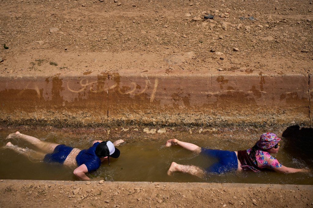 Two boys slide down into a spring as Israeli settlers and others enjoy a day in the Jordan Valley during Israel's Independence Day, in Auja, in the occupied West Bank, Wednesday, April 22, 2026.(AP Photo/Ohad Zwigenberg)