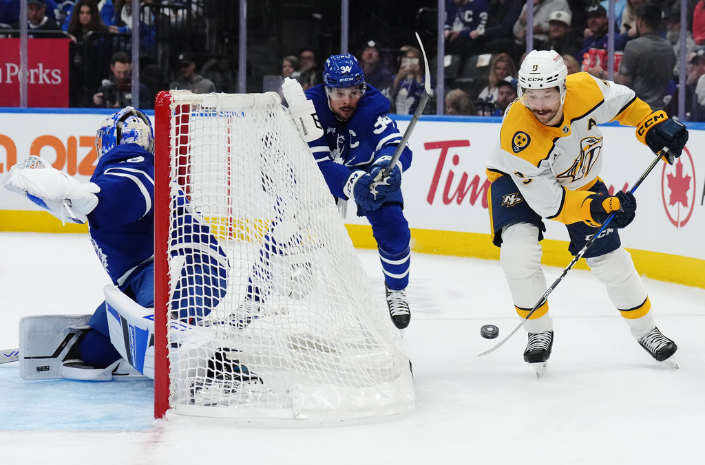 Nashville Predators' Filip Forsberg (9) protects the puck from Toronto Maple Leafs' Auston Matthews (34) behind goaltender Cayden Primeau (30) during first period NHL hockey action in Toronto on Tuesday, Oct. 14, 2025. (Nathan Denette/The Canadian Press via AP)