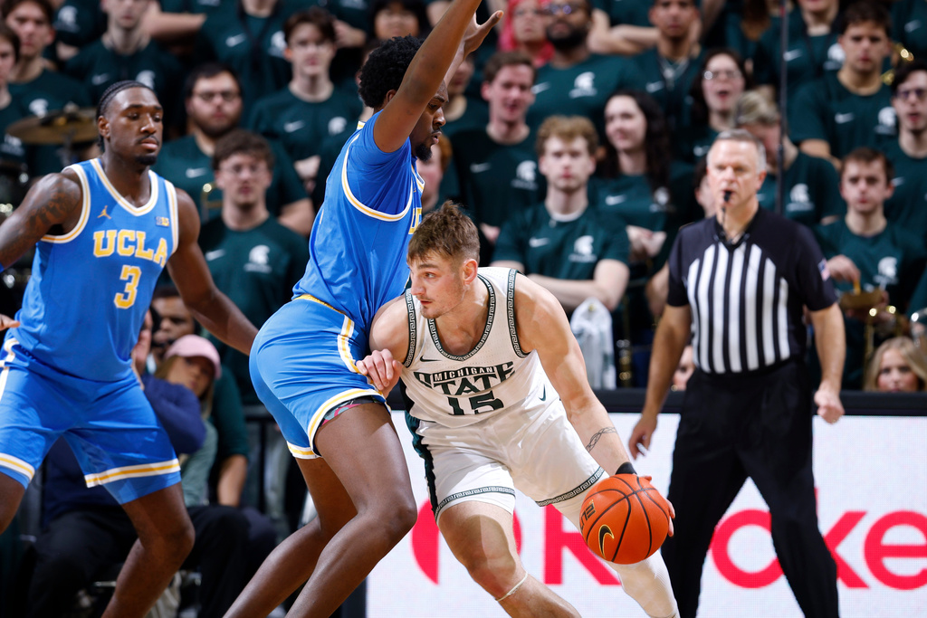 Michigan State center Carson Cooper (15) drives toward UCLA center Xavier Booker and forward Eric Dailey Jr. (3) during the first half of an NCAA college basketball game, Tuesday, Feb. 17, 2026, in East Lansing, Mich. (AP Photo/Al Goldis)