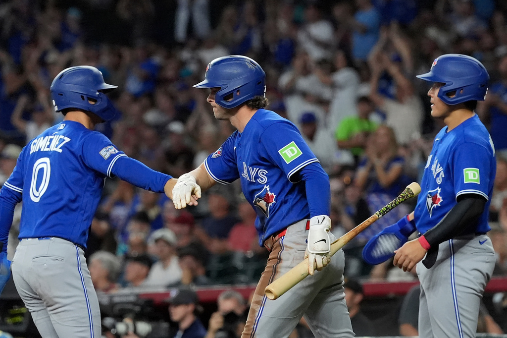 Toronto Blue Jays'Andres Gimenez (0) celebrates his run scored against the Arizona Diamondbacks with Blue Jays' Ernie Clement (22) as Blue Jays' Kazuma Okamoto, right, of Japan, looks on during the first inning of a baseball game, Sunday, April 19, 2026, in Phoenix. (AP Photo/Ross D. Franklin)