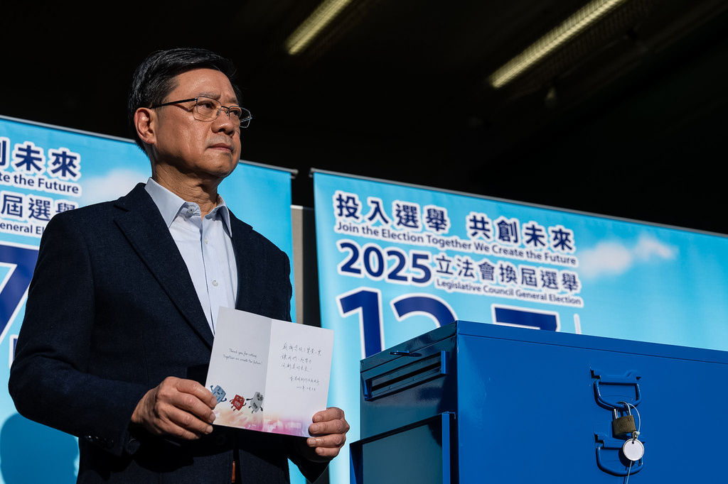 Hong Kong's Chief Executive John Lee, poses for photos at a polling station during the Legislative Council General Election in Hong Kong on Sunday, Dec. 7, 2025. (AP Photo/Chan Long Hei)