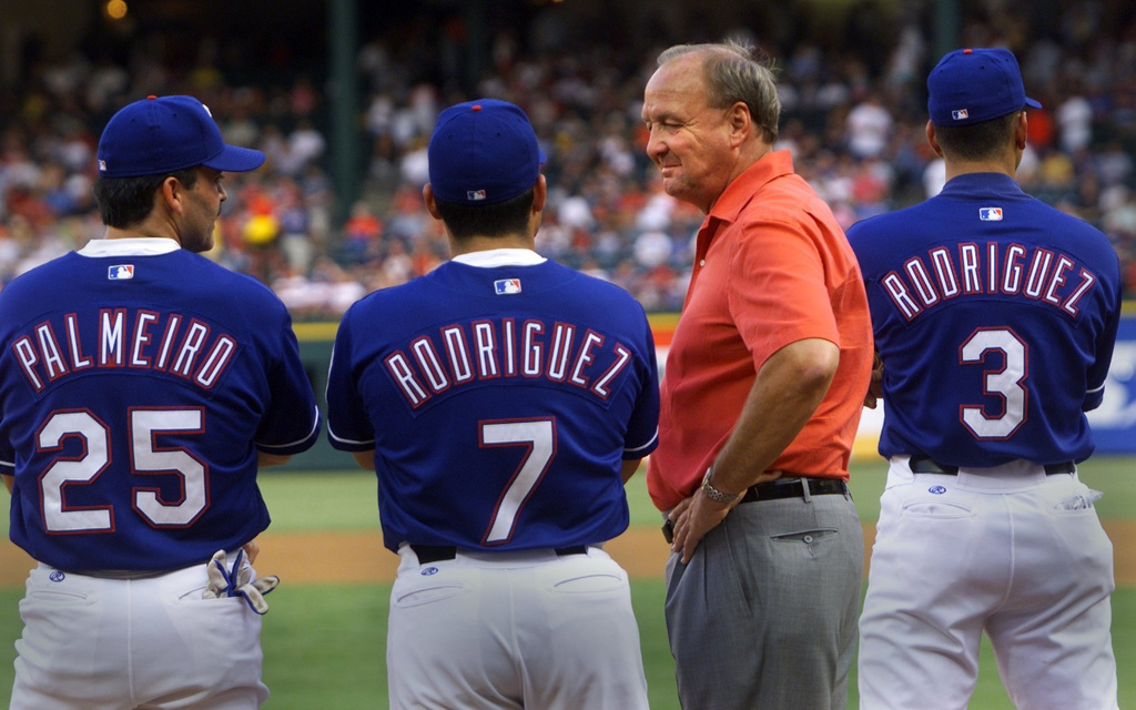 Texas Rangers owner Tom Hicks, second right, and players Rafael Palmeiro, Ivan Rodriguez, and Alex Rodriguez, stand together during a baseball game, July 26, 2001, in Arlington, Texas. (Huy Nguyen/The Dallas Morning News via AP)
