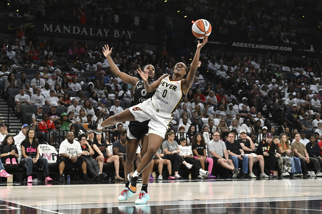 Indiana Fever guard Kelsey Mitchell, right, shoots against Las Vegas Aces guard Jackie Young, left, in the second half of Game 1 of a WNBA basketball playoff semifinals series Sunday, Sept. 21, 2025, in Las Vegas. (AP Photo/Candice Ward)