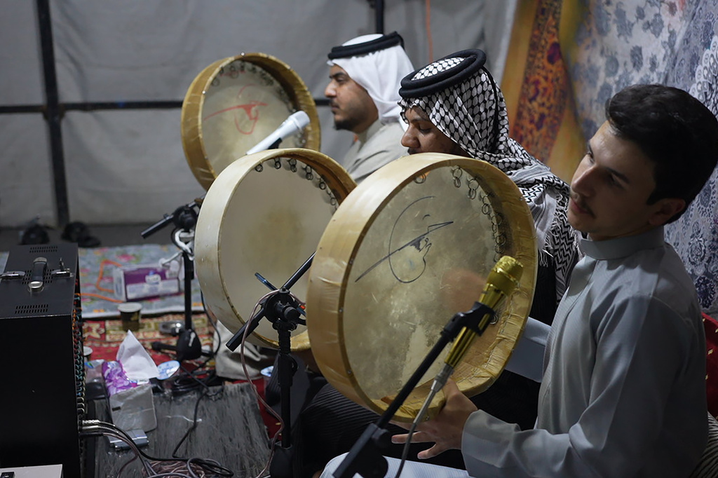 Musicians beat the daf drum as they perform traditional mourning songs for men gathered under a tent outside the family home of Iraqi singer Sajida Obaid on the seventh day of her passing in Irbil, Iraq, Thursday, April 10, 2026. (AP Photo/Stella Martany)