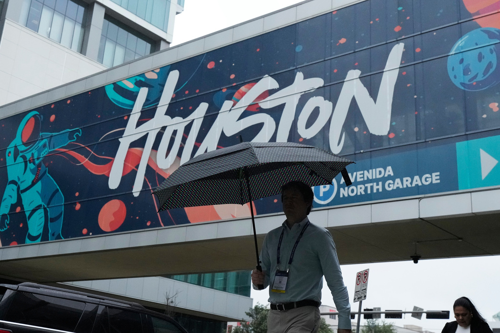 A convention attendee walk through the rain outside the George R. Brown Convention Center, Wednesday, June 17, 2026, in Houston. (AP Photo/Kevin M. Cox)