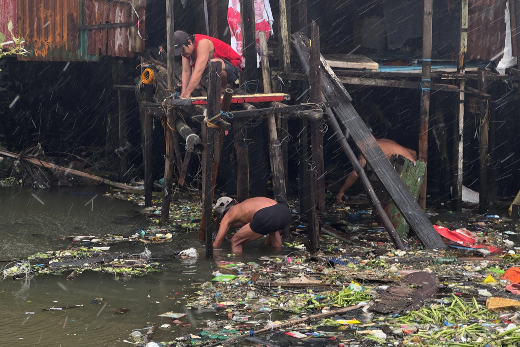 Residents fix their home during rain due to Typhoon Fung-wong along a coastal village on Monday, Nov. 10, 2025, in Navotas, Philippines. (AP Photo/Aaron Favila)