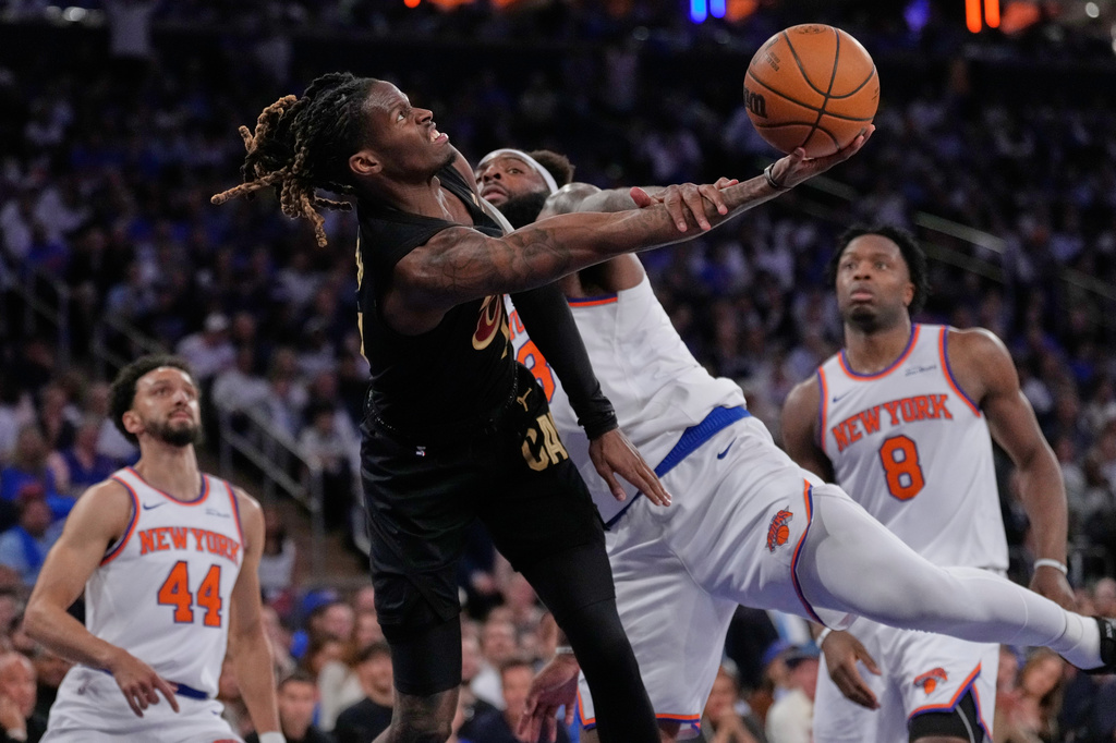 New York Knicks' Mitchell Robinson, center right, fouls Cleveland Cavaliers' Keon Ellis, center left,who goes looks to shoot during the first half of Game 1 in the Eastern Conference finals NBA basketball playoffs series, Tuesday, May 19, 2026, in New York. (AP Photo/Seth Wenig)
