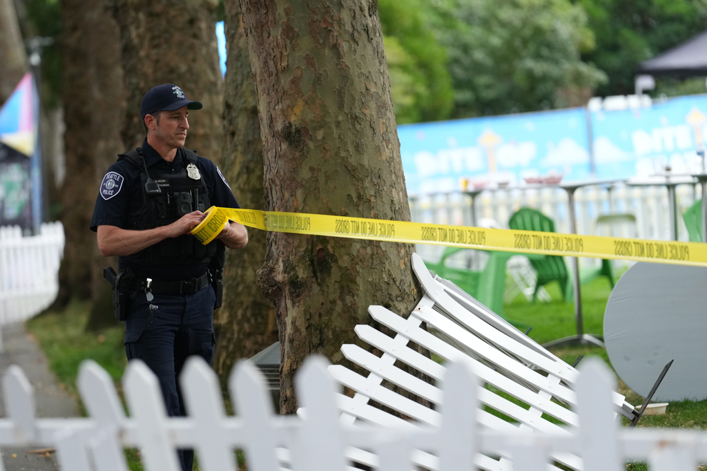 A Seattle Police officer sets up police line tape at the site of a shooting at Seattle Center during the Bite of Seattle food festival Sunday, July 26, 2026, in Seattle. (AP Photo/Lindsey Wasson)
