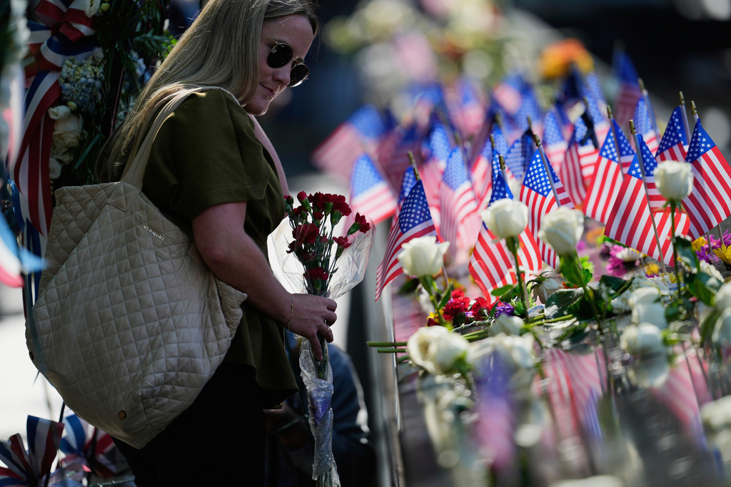 Jaclyn O'Connor places flowers on the 9/11 Memorial during a ceremony to mark the 24th anniversary of the 9/11 attacks, Thursday, Sept. 11, 2025, in New York. (AP Photo/Seth Wenig)