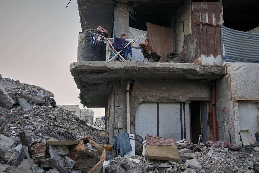 Two girls sit next to their drying laundry in a gutted apartment building in Gaza City, Tuesday, Nov. 18, 2025. (AP Photo/Jehad Alshrafi)